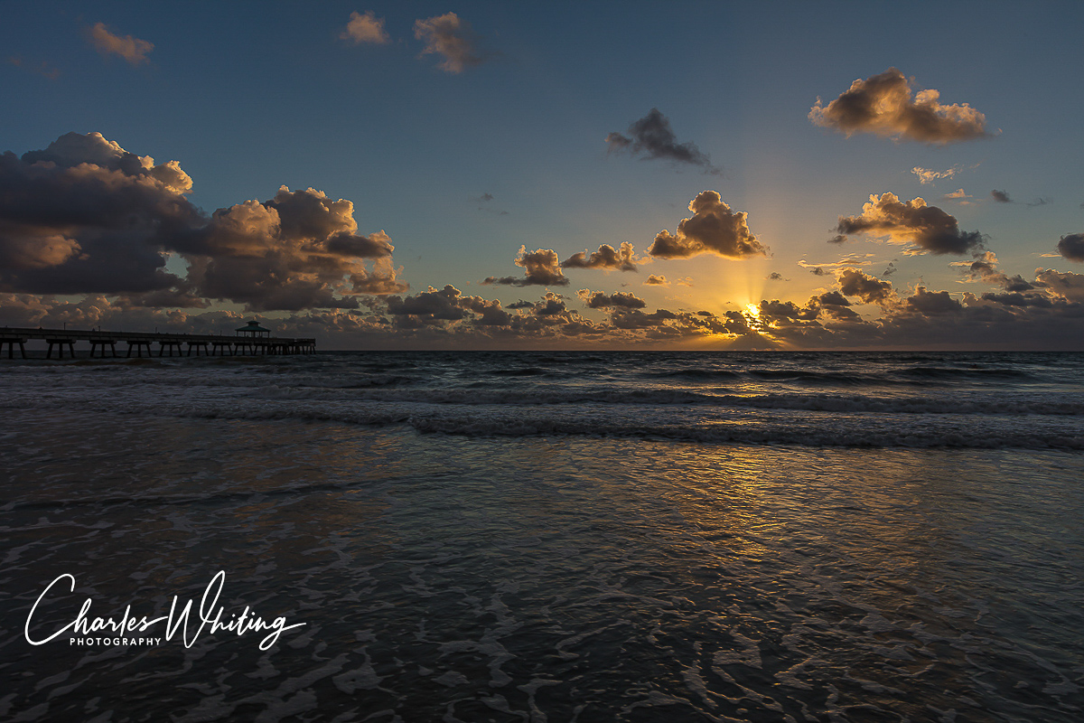 The morning sun lights up the clouds around the Deerfield Beach fishing pier