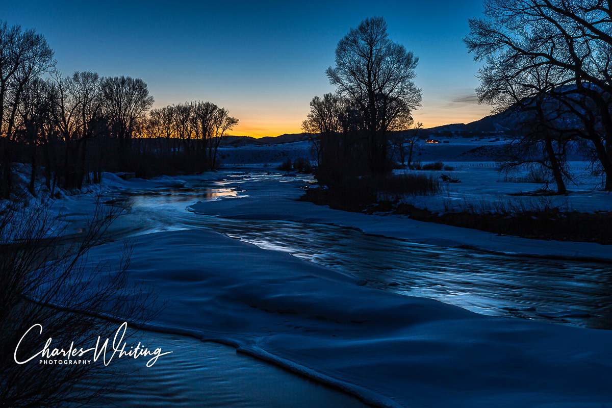 Elk Creek illuminated by the last light of the day with house lights shining in the distance. Steamboat Springs, Colorado