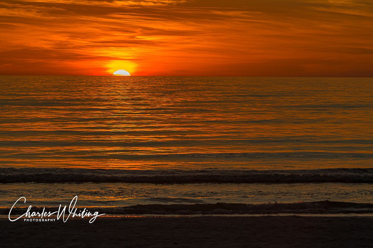 The setting sun paints the sky and water a brilliant red