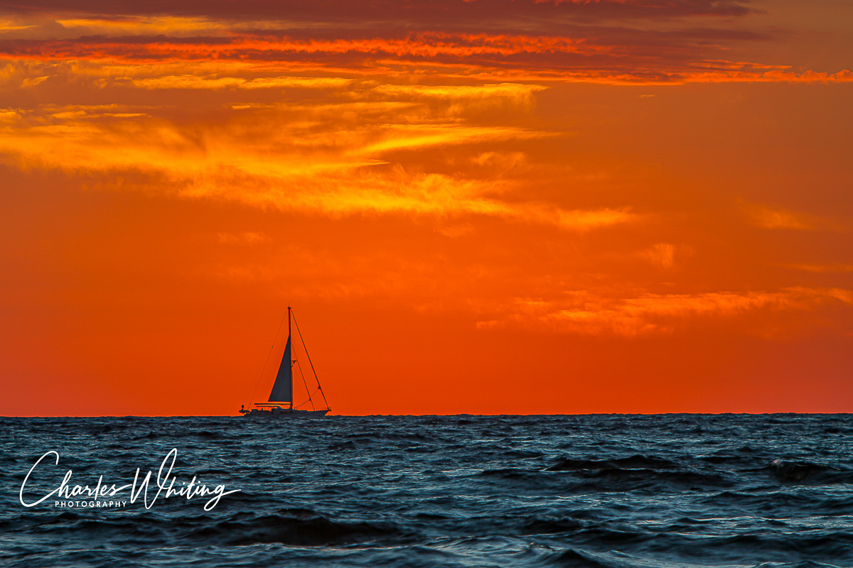 A sailboat caught in silhouette by the rising sun